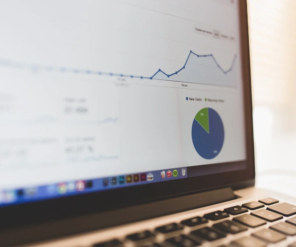 A laptop displaying a website analytics dashboard with graphs and charts showing visitor traffic trends and statistics.