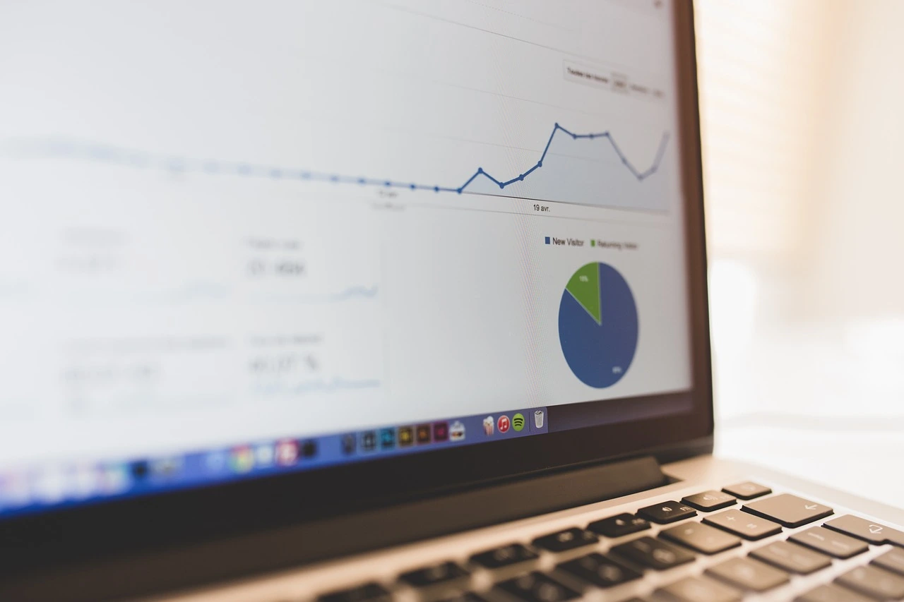 A laptop displaying a website analytics dashboard with graphs and charts showing visitor traffic trends and statistics.